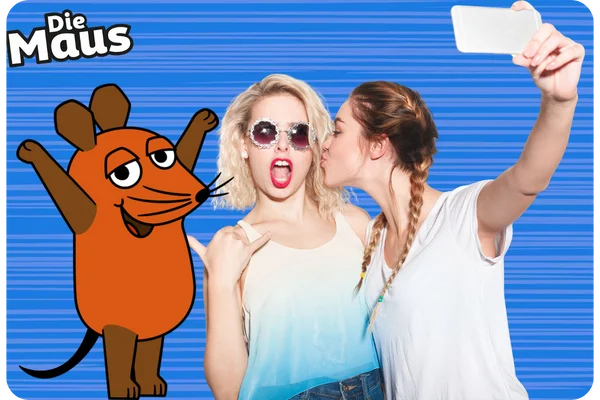 Partygäste machen ein Selfie mit der Maus-Fotobox Zwei junge Frauen posieren lachend für ein Selfie. Eine der Frauen trägt eine Sonnenbrille und macht einen lustigen Ausdruck. Die Figur "Die Maus" ist als Fotobox-Overlay sichtbar.
