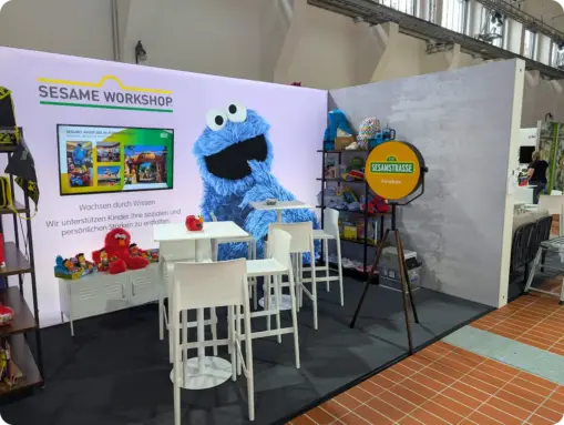 Der Messestand des Sesame Workshop in der Messe Essen mit großem Krümelmonster-Wandbild und einer passend gelb gebrandeten Fotobox.